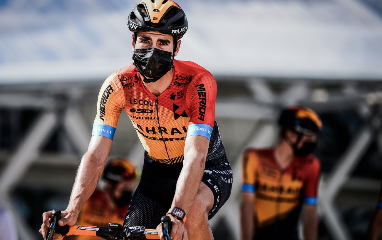 Landa in an orange and red Bahrain Victorious jersey wearing a mask.