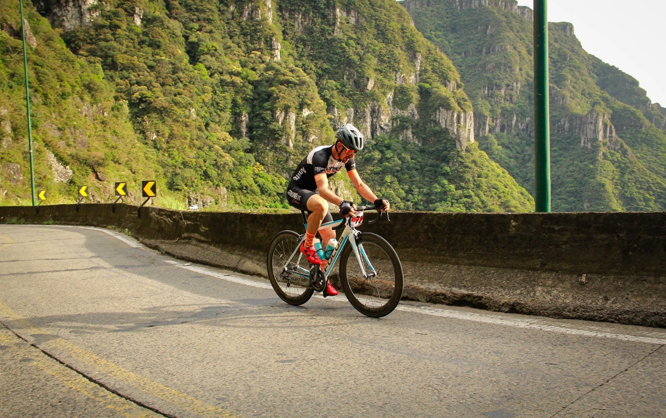 A cyclist in full lycra takes on a sub-tropical climb on a turquoise and white road bike.