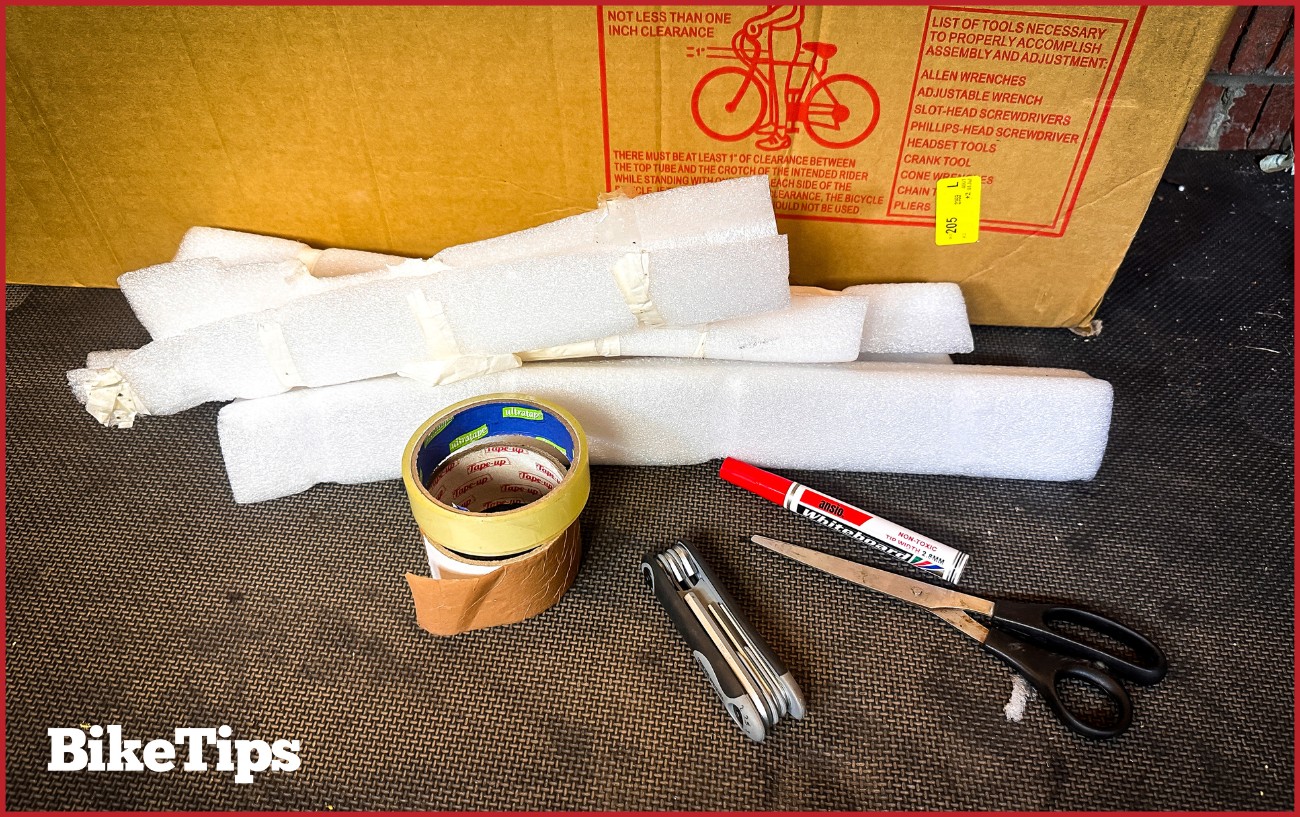 Tape, scissors, bike box, Allen keys, packaging, and a marker pen. Everything used to pack a bike. 