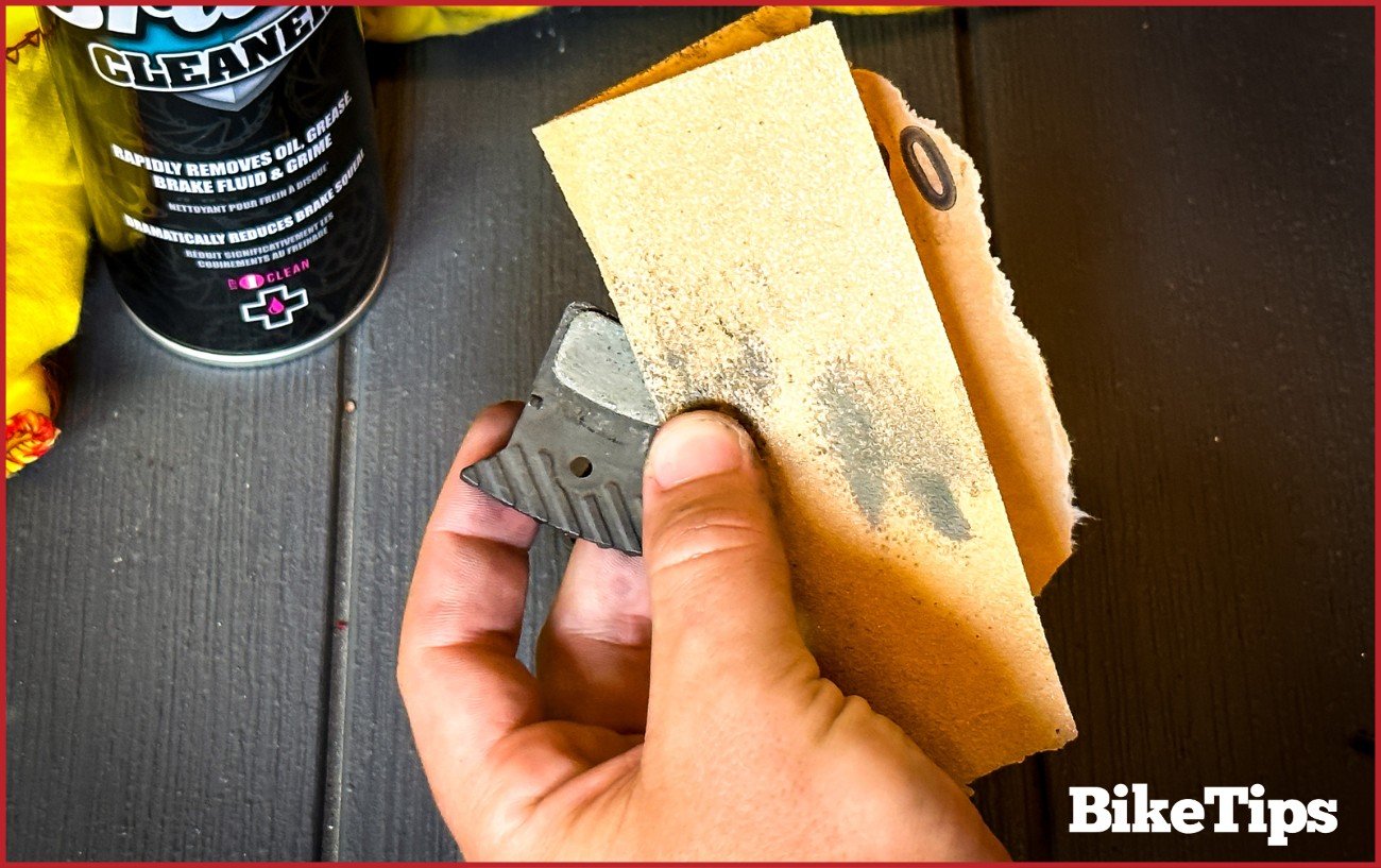 Using sand paper to rough up bike brake pads.