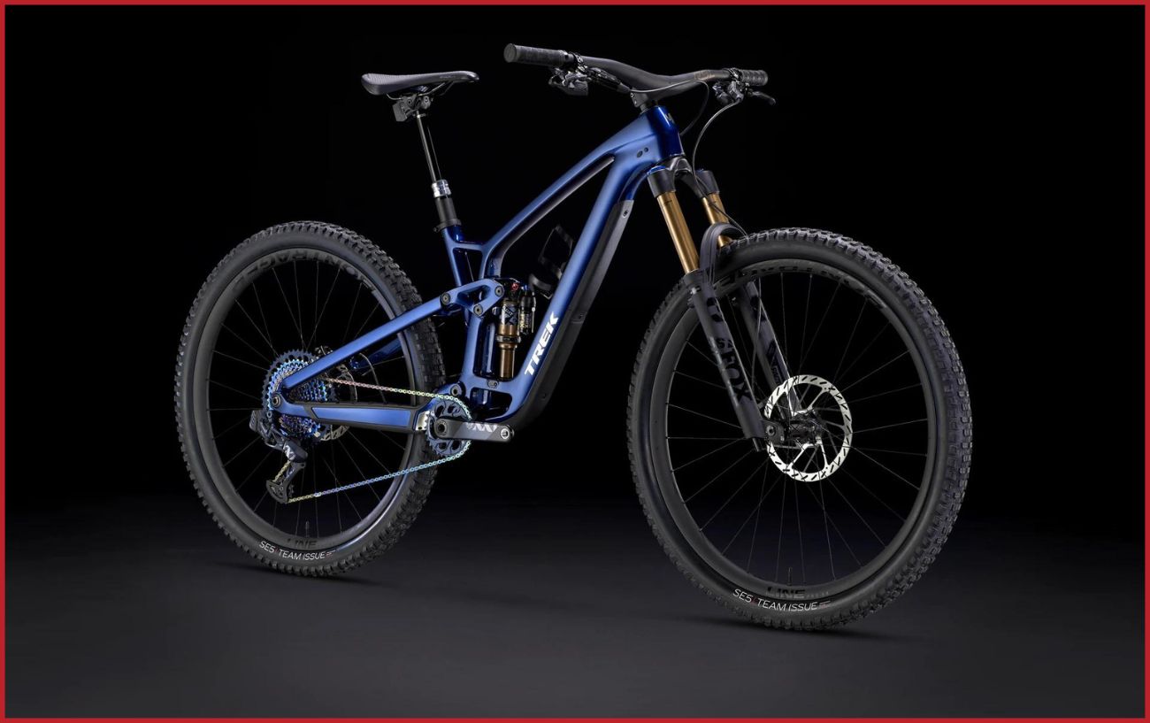 Blue full suspension mountain bike with orange forks and mountain bike tyres with black background. 