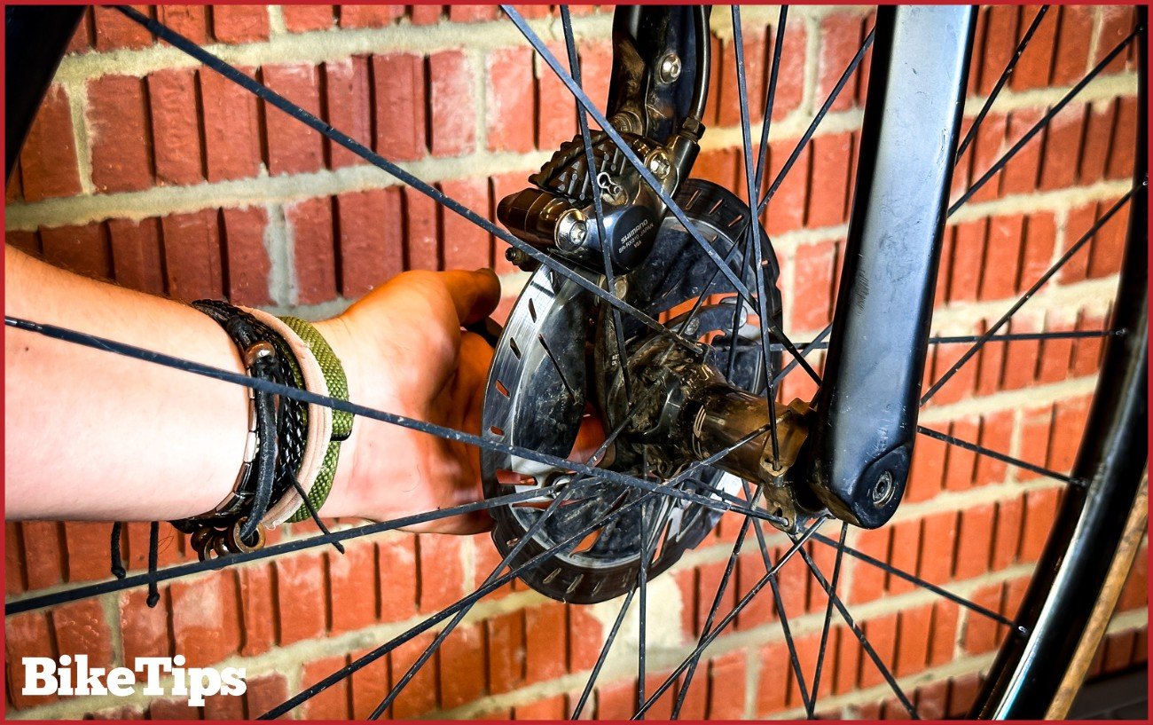 Inserting a front wheel into a disc brake bike and tightening the thru axle. 