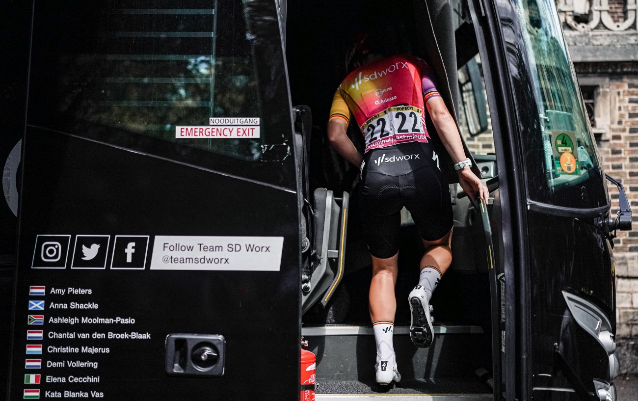 A Tour de France rider climbs aboard their team bus.