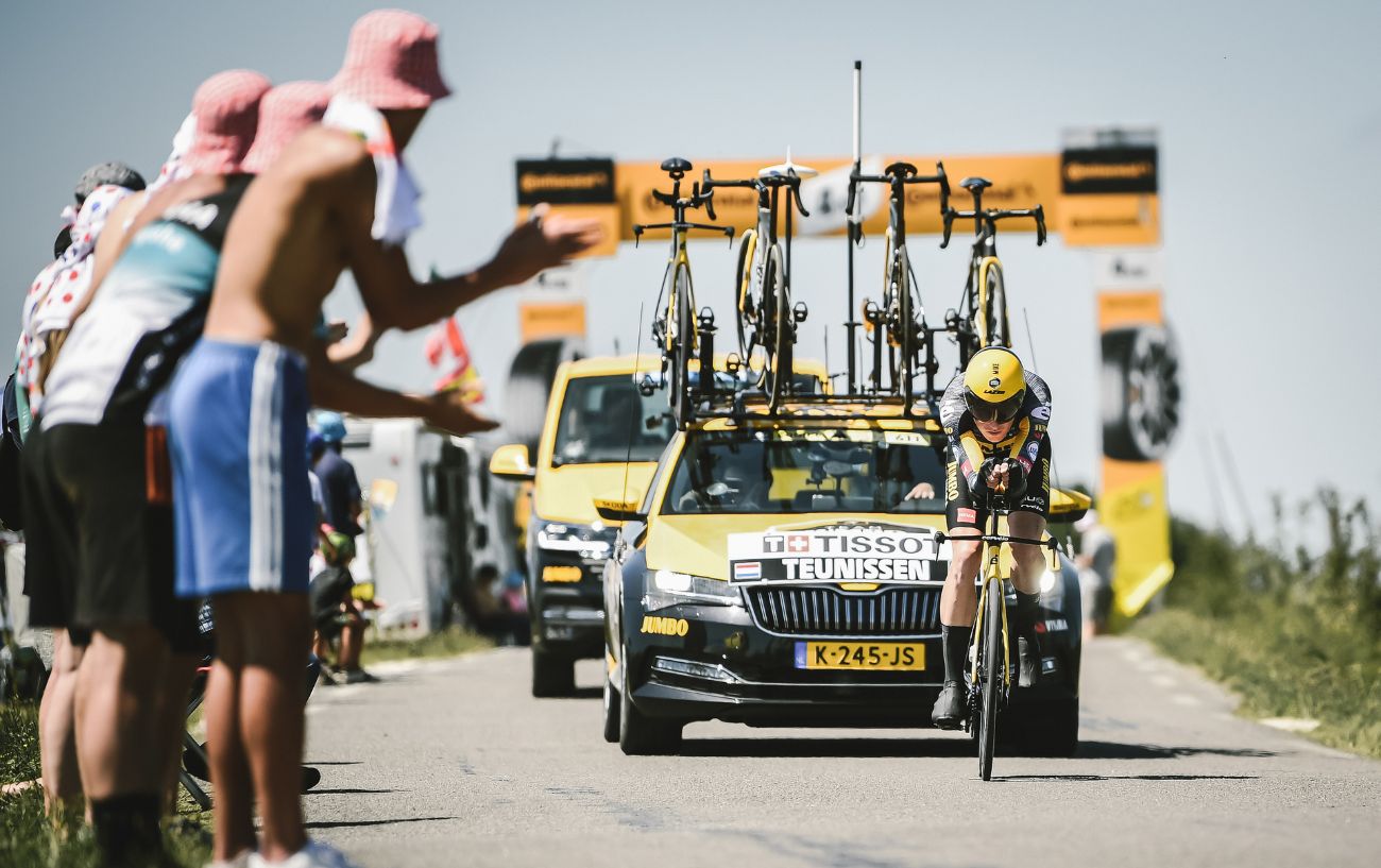 A team Jumbo-Visma Tour de France mechanic truck follows a cyclist on a Tour de France time trial stage.