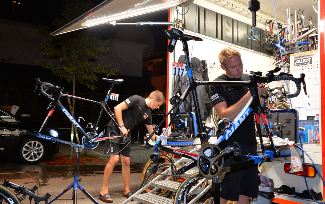 Two bikes are maintained from the back of a Tour de France mechanic's truck late at night.