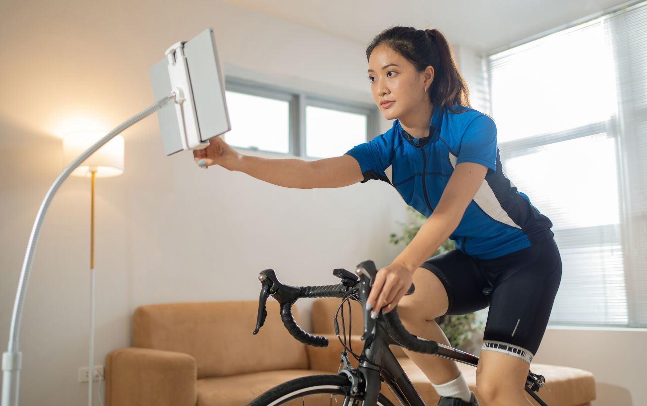 Woman wearing black and blue cycling clothes sits on an indoor bicycle. 