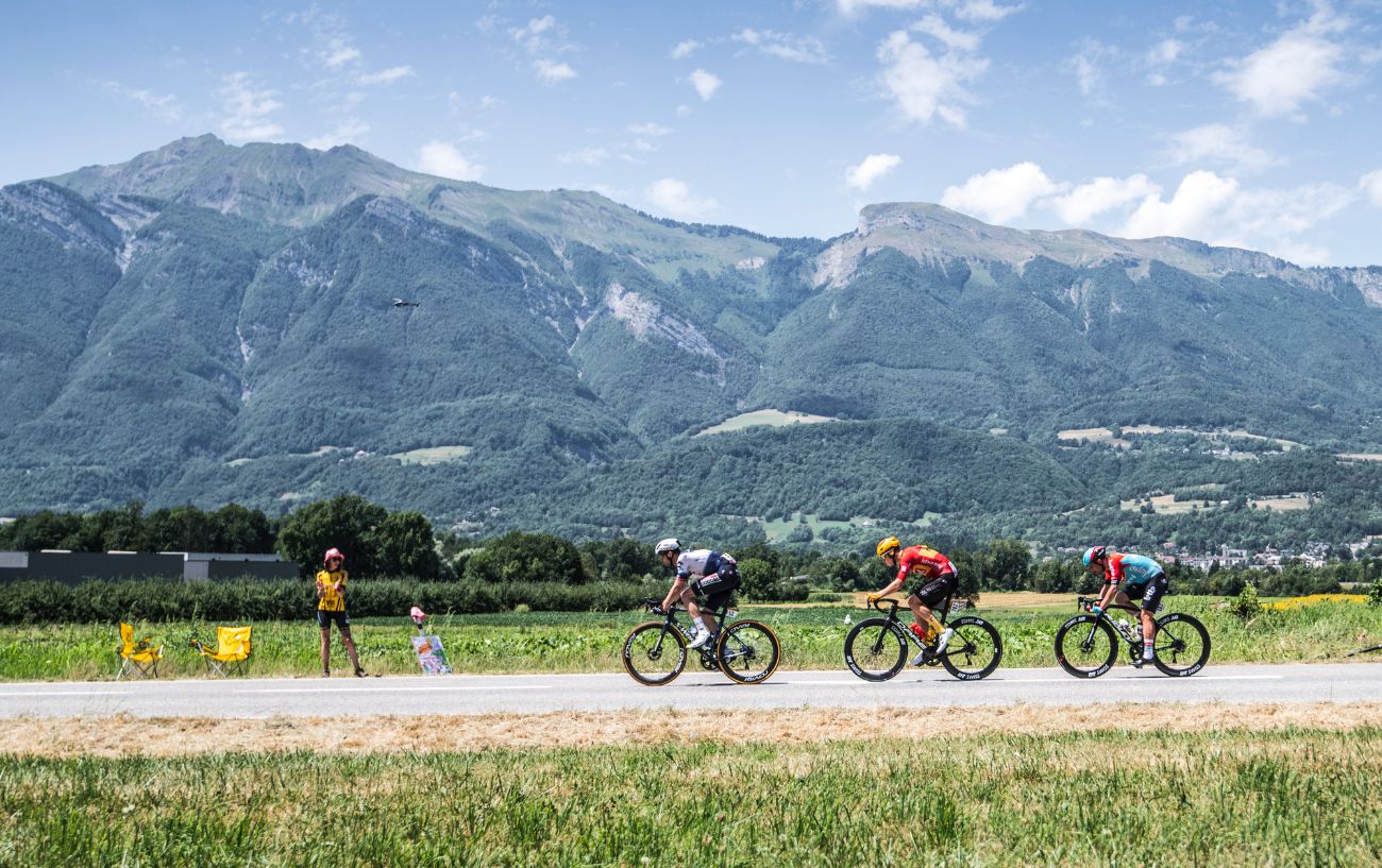 Three riders at the 2023 Tour de France with the Alps in the background.