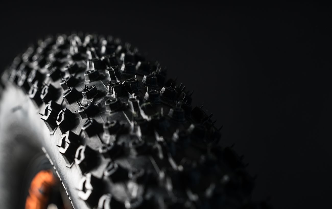 Brand new mountain bike tire with lots of tread and a black background behind it. 