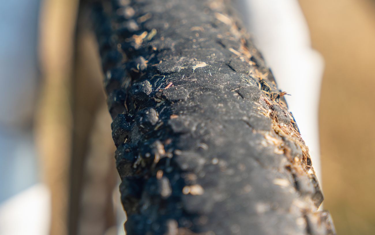 An old mountain bike tire covered in dirt with severely worn out tread. 