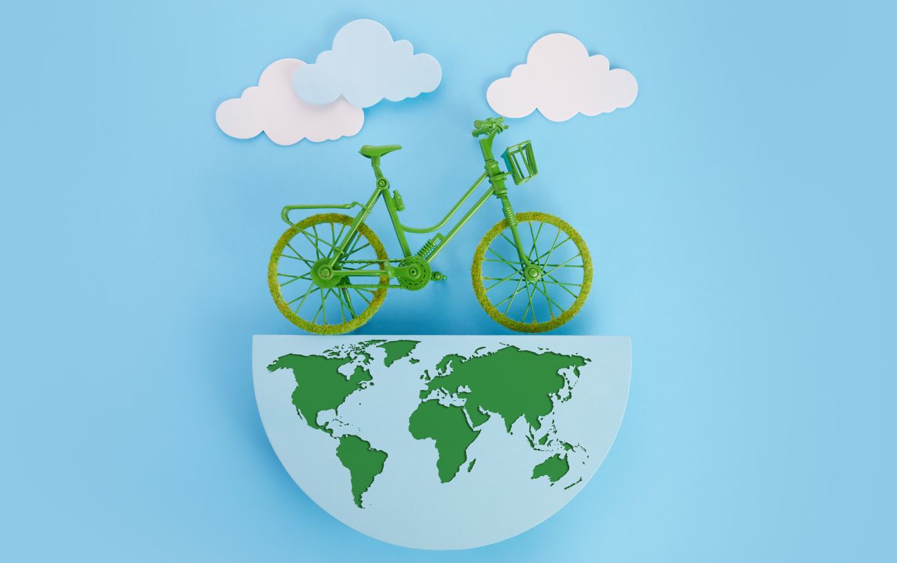 A green bike rests upon a model version of the world with a white and blue background. 