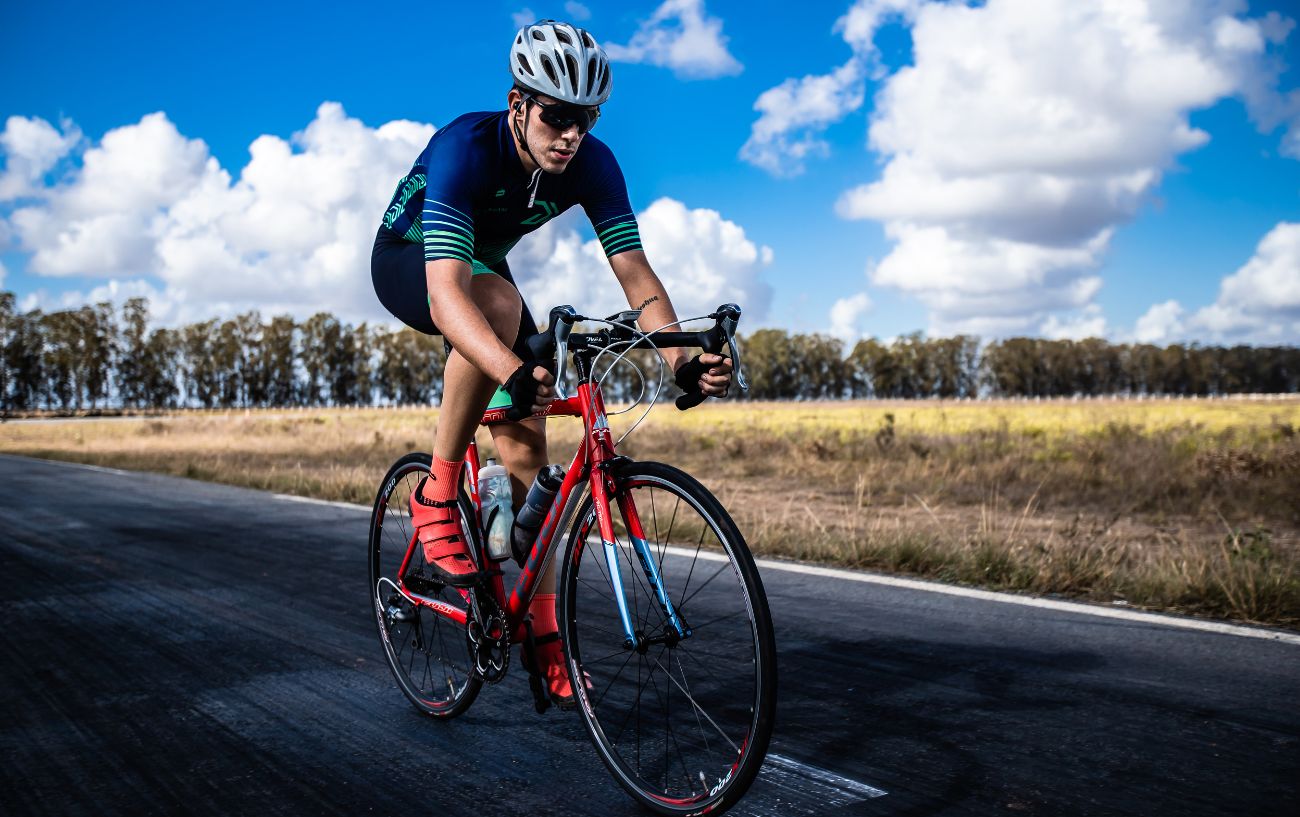 A cyclist rides an orange road bike on a racetrack.