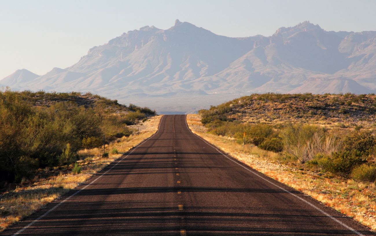 Photo of an asphalt road with mountains on the horizon in Texas.