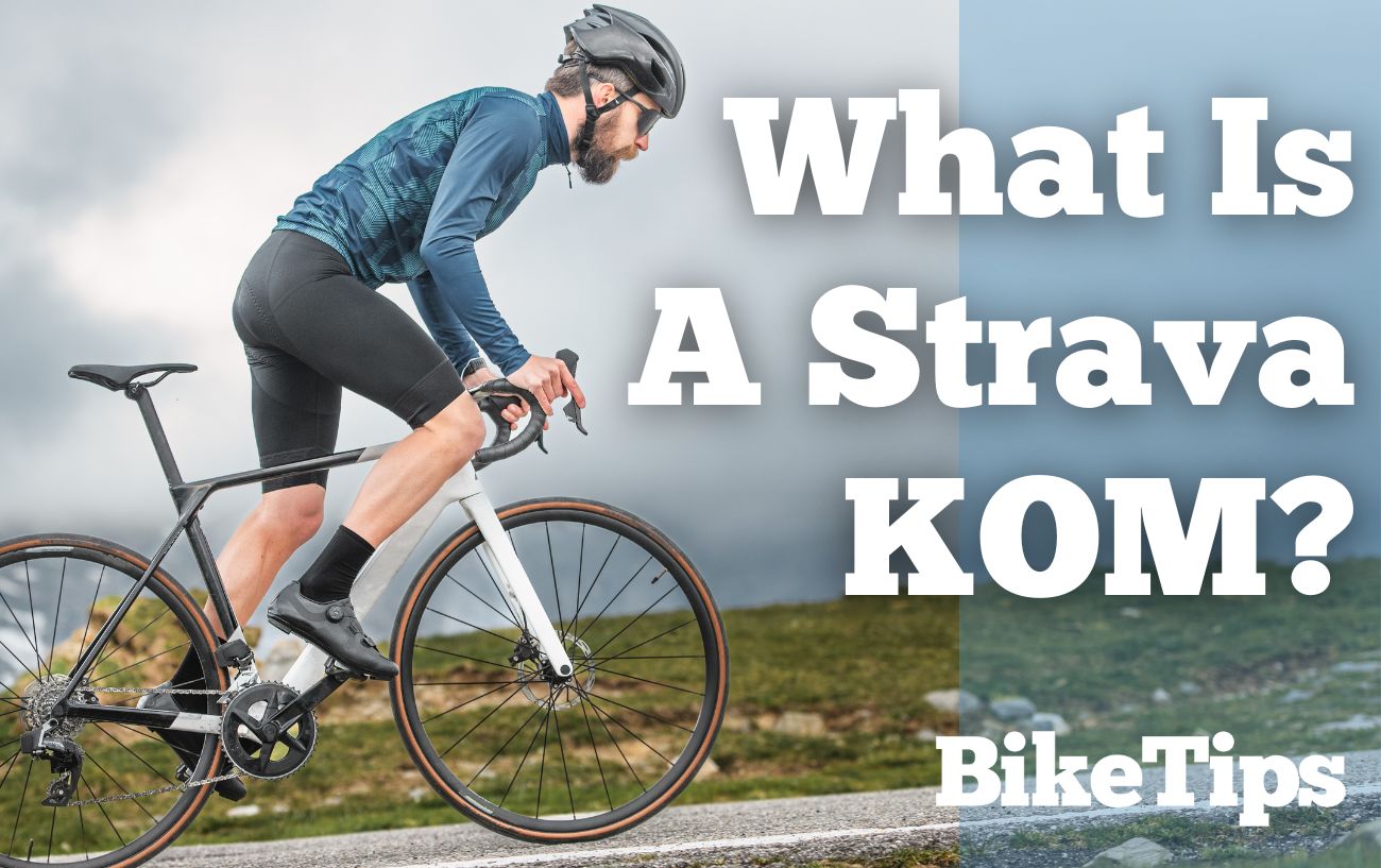 Man wearing blue top and black shorts cycles uphill with the words "What Is A Strava KOM?" in the foreground.
