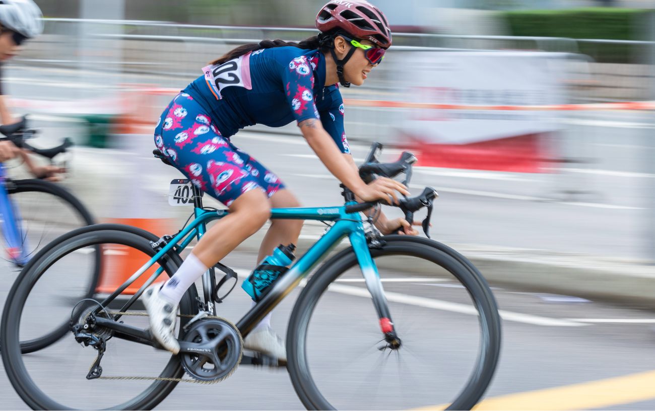 A cyclist on a turquoise road bike rounds a corner during a race.