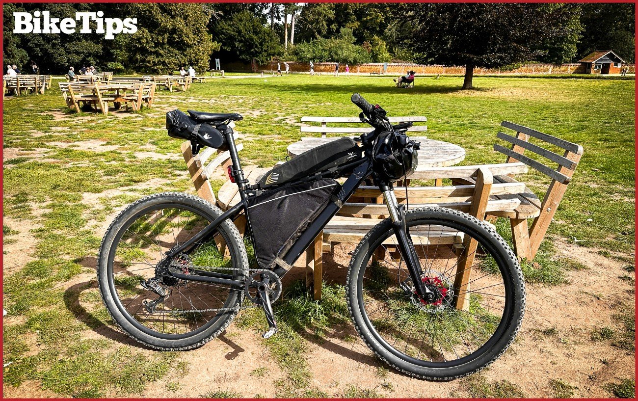 A bikepacking mountain bike against a bench.