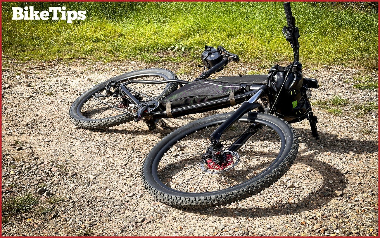 A bikepacking mountain bike front on, laying on a gravel trail.