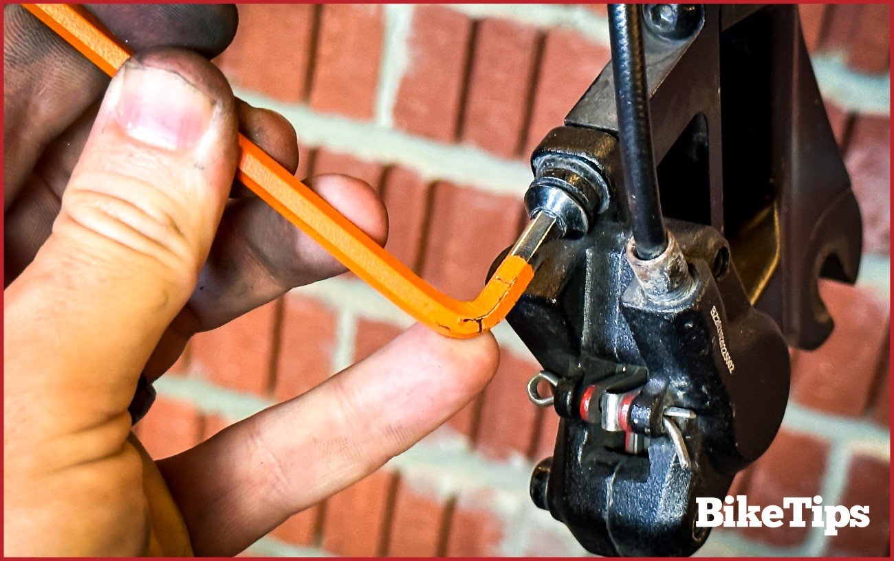 Loosening the caliper bolts on a hydraulic disc brake.