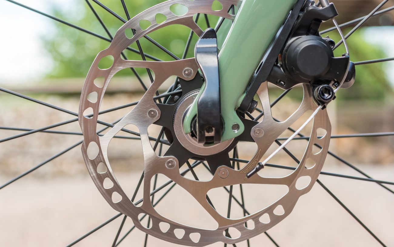 A green coloured bike with a shining front disc brake.