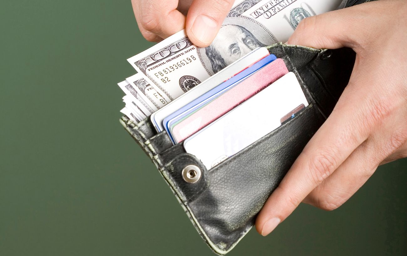 A wallet with cards and money in it with a green background.