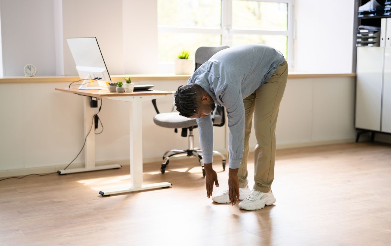 An office worker stretches next to his desk.