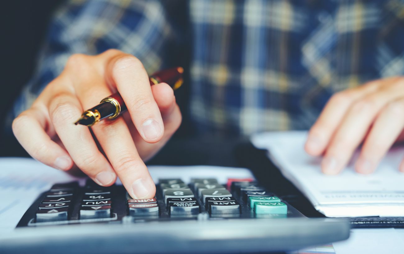 A person uses a calculator with a pen in their hand.