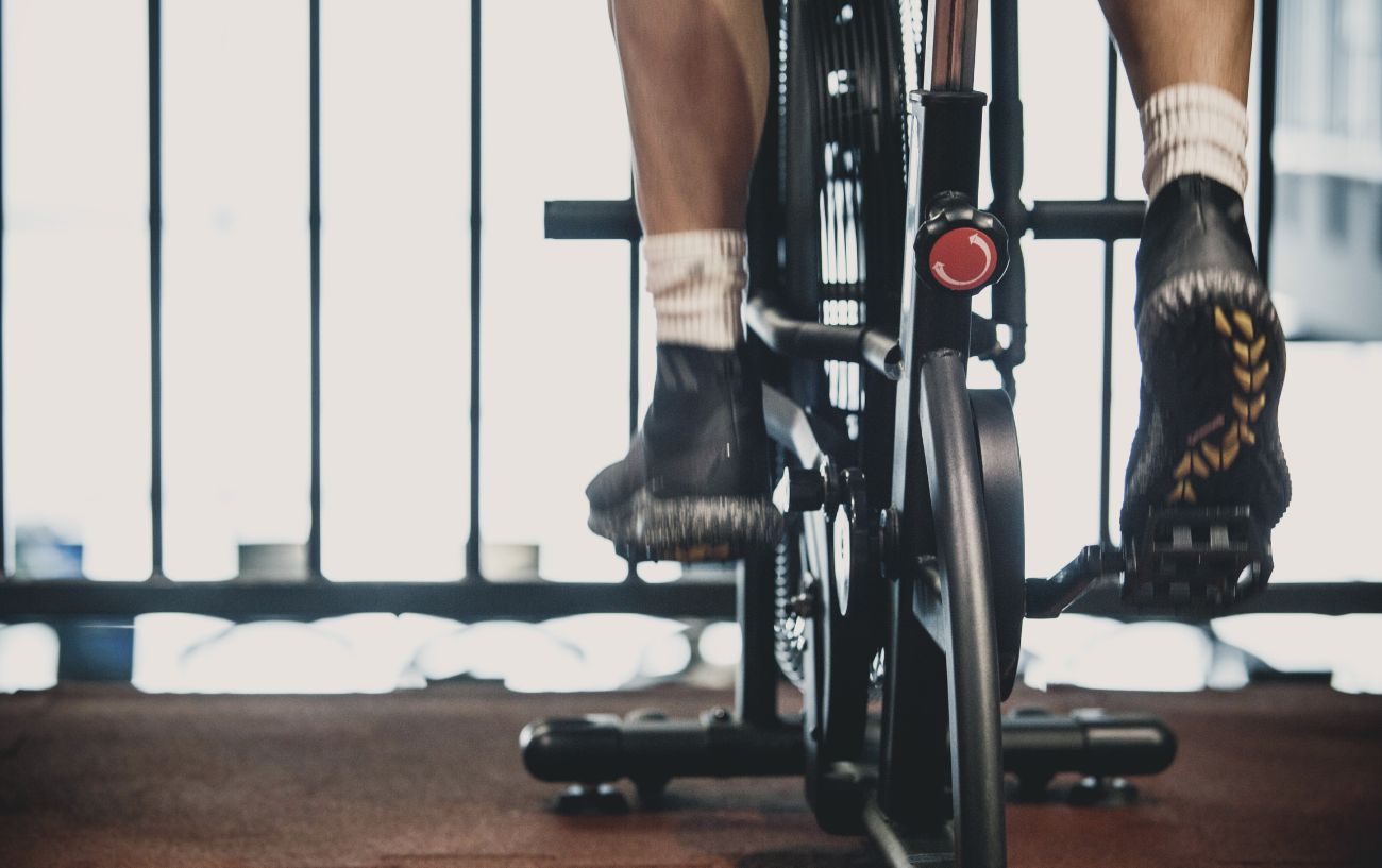 A person sits on a stationary bicycle with a blurred background.