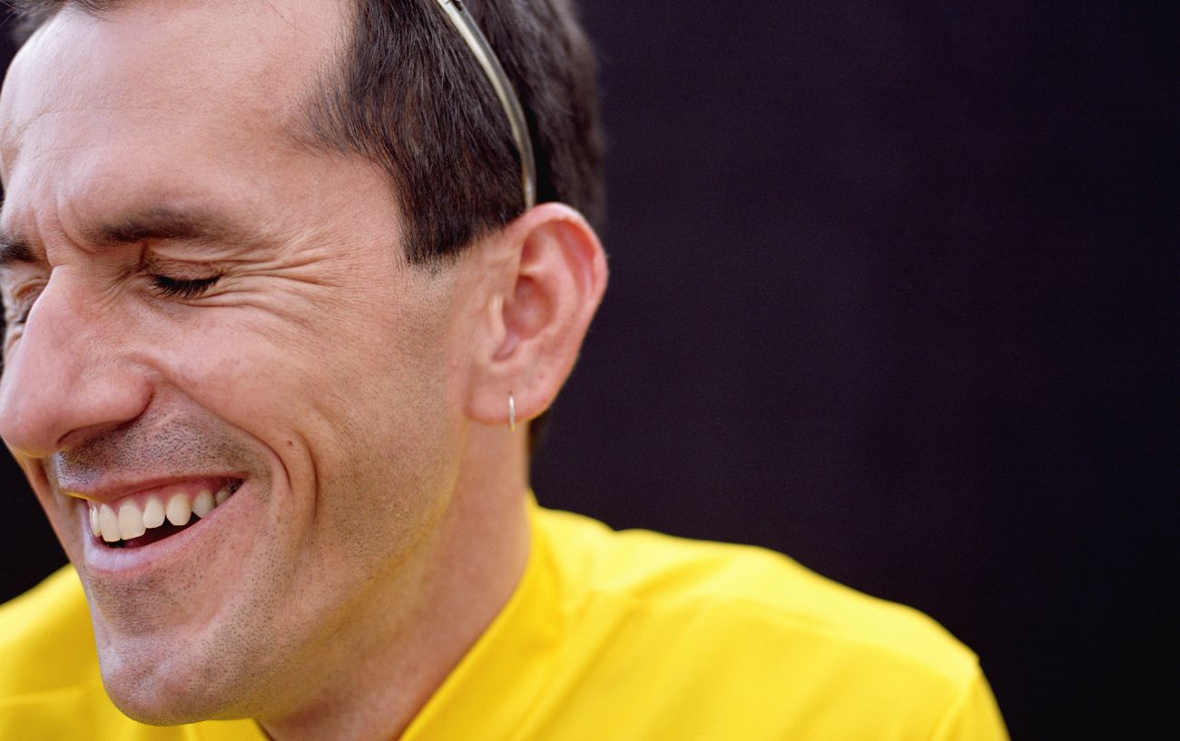 A cyclist in a yellow jersey laughs at a bike joke.