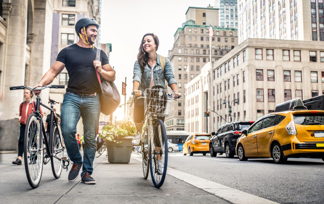 A couple riding bikes in New York laugh at a bike joke.