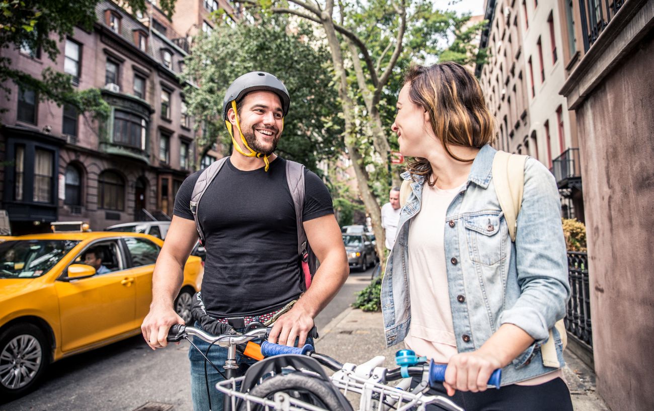 A couple on bicycles in New York laugh at a bike joke.