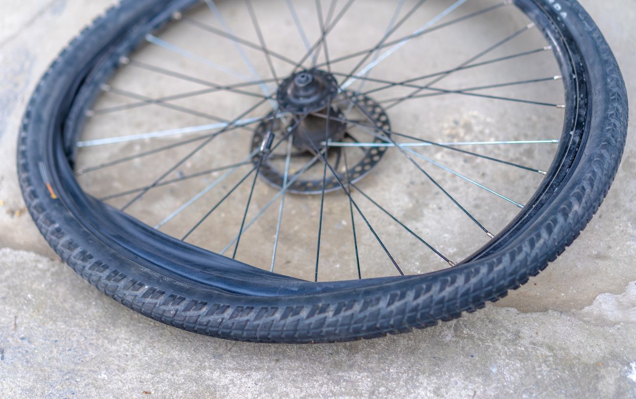 A gravel bike tire sits on the concrete floor with the inner tube being removed.