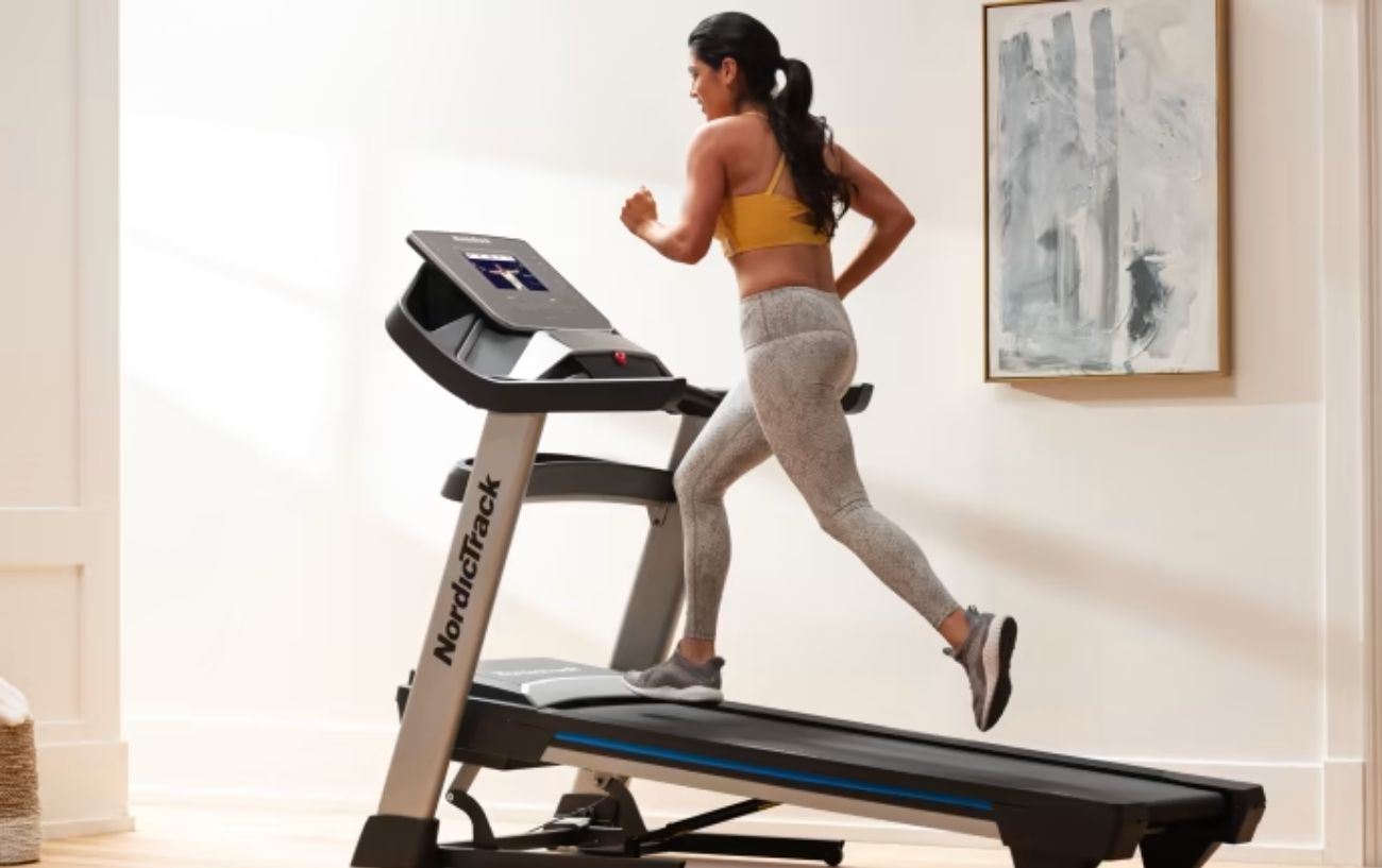 A woman runs on an incline NordicTrack treadmill.