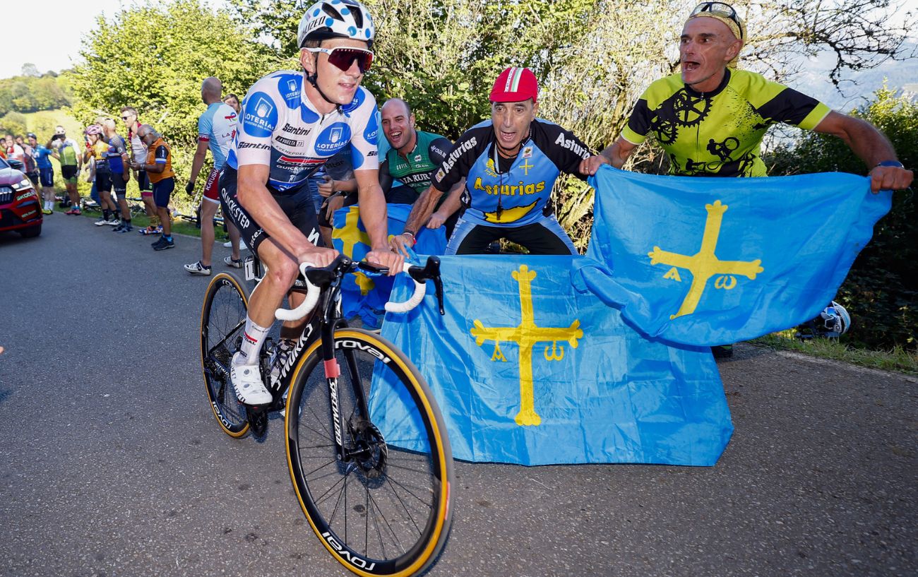 Remco Evenepoel rides past fans waving Asturian flags on his way to victory at Stage 18 of the 2023 Vuelta a Espana.