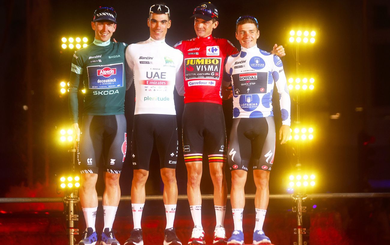 Kaden Groves, Juan Ayuso, Sepp Kuss, and Remco Evenepoel pose in their respective jerseys on the podium of the 2023 Vuelta a Espana.