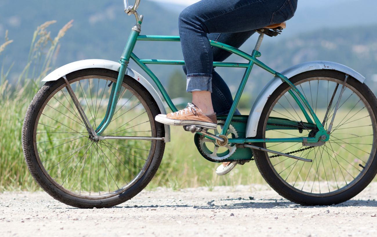 A person rides a blue cruiser bike along a gravel path.