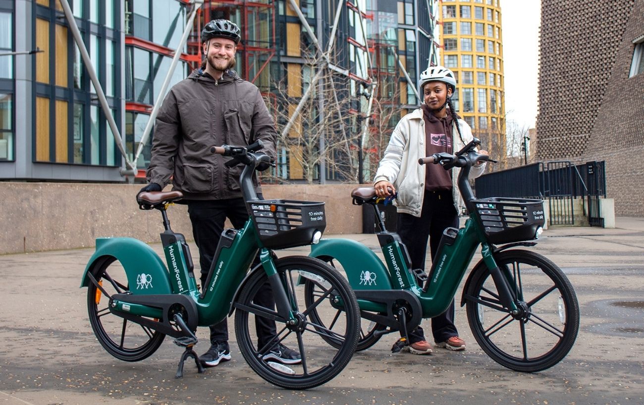 Press photo of two people holding HumanForest eBikes next to London's TATE Modern.