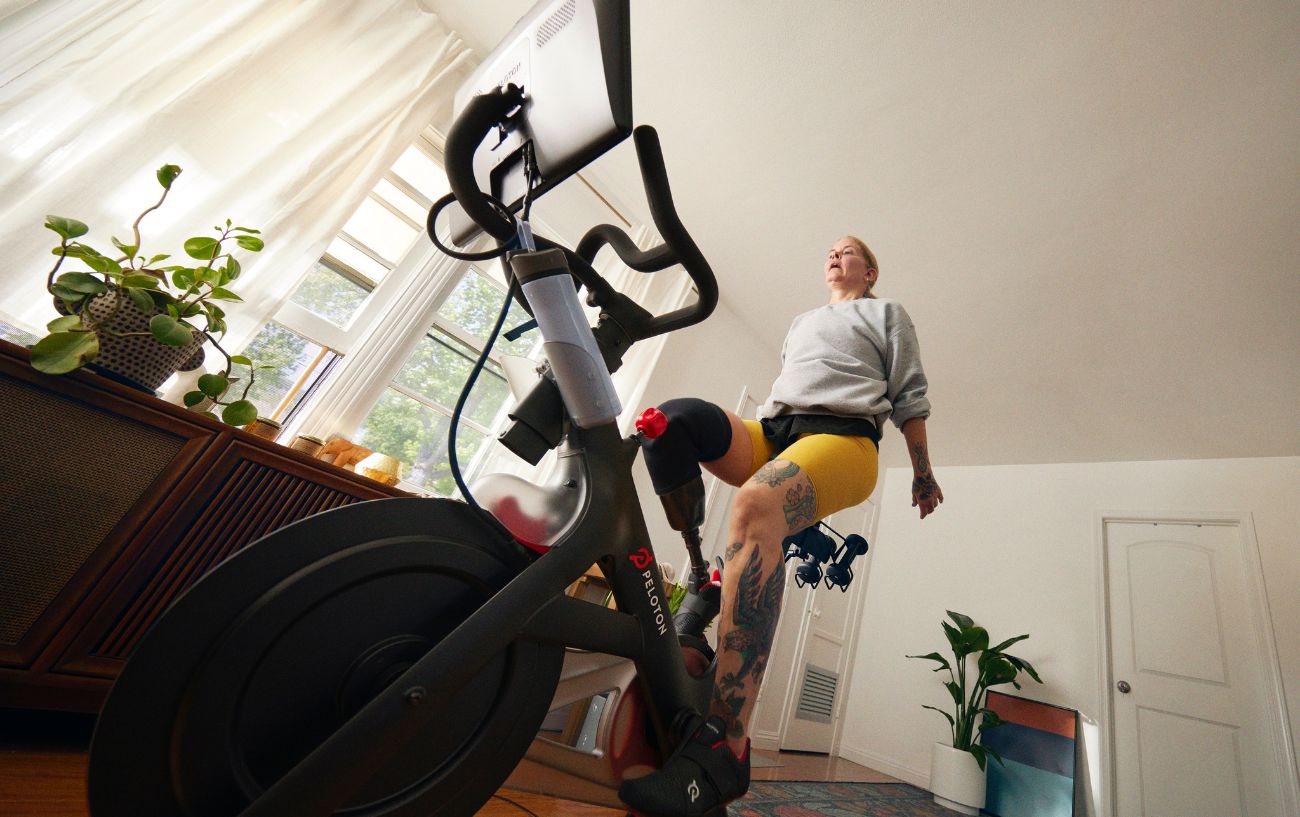 A woman rides a Peloton bike in her home.