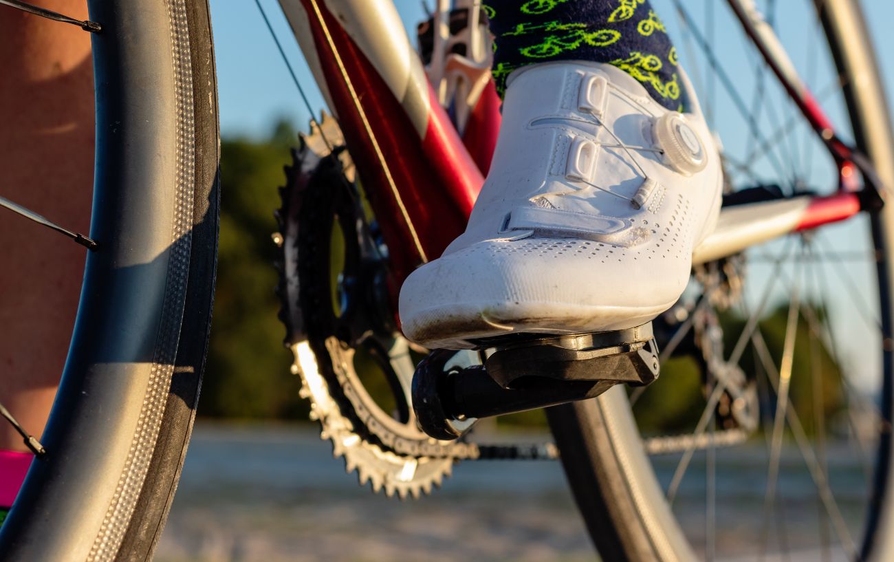 A cyclist with white cycling shoes on demonstrates "float" in clipless bike pedals.