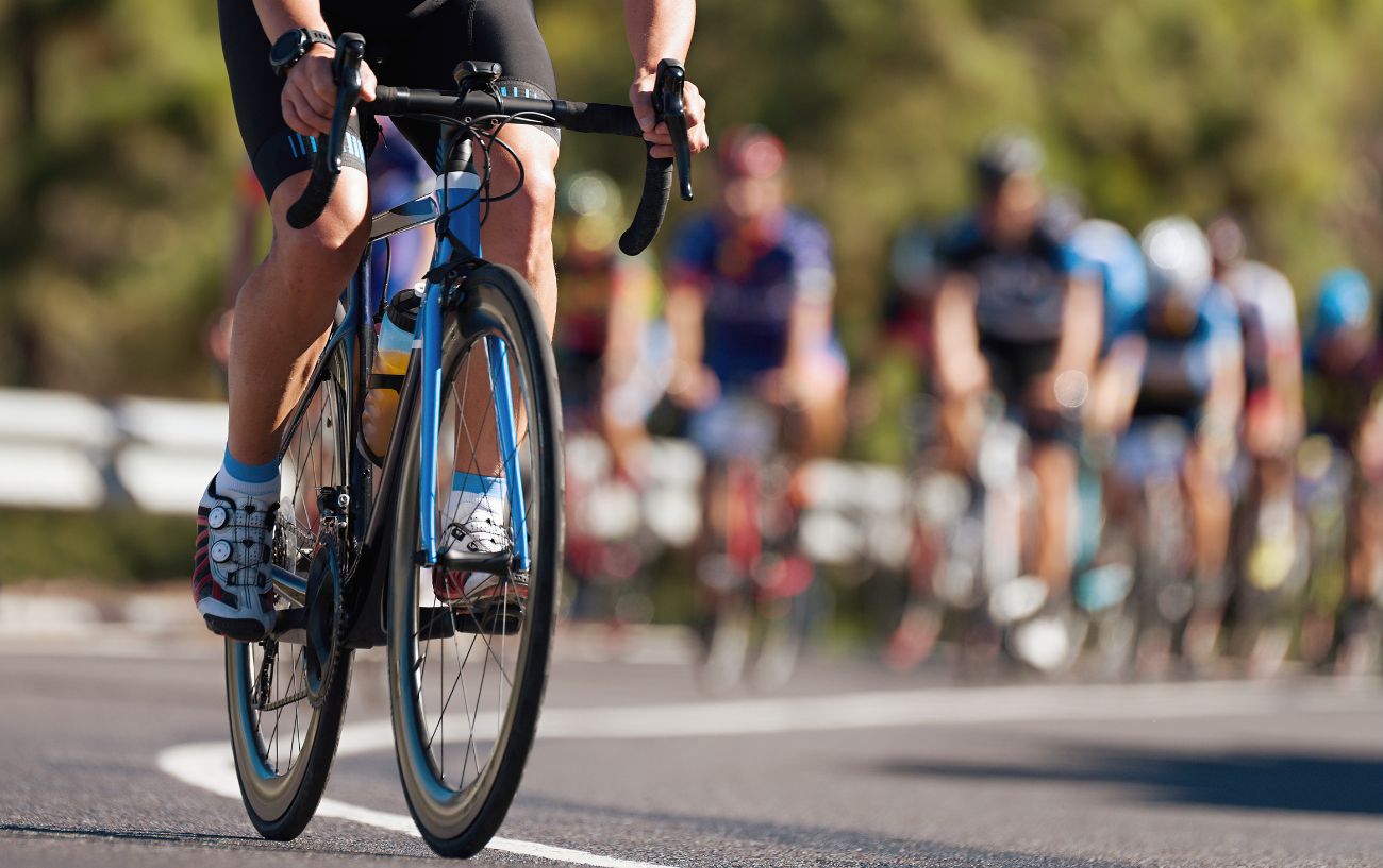 A cyclist on a blue road bike leads the peloton up a steep climb during a race.