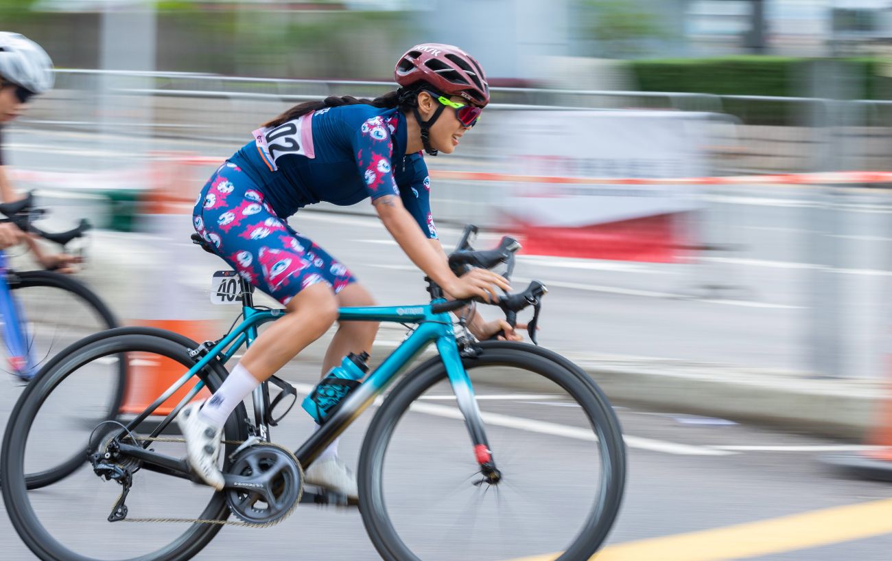 A professional cyclist rides at a high cycling cadence during a criterium race.