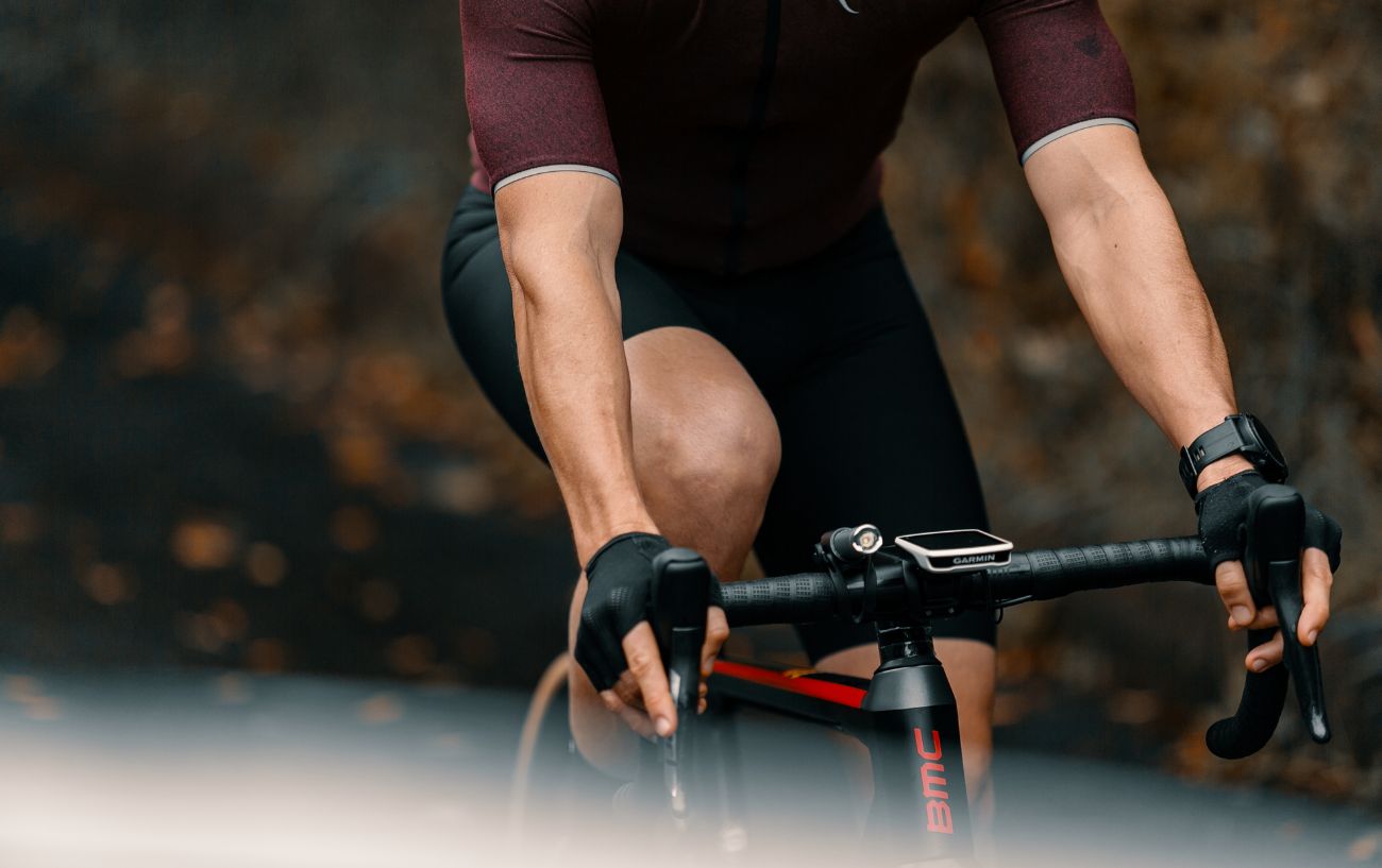 A cyclist rides a black road bike fitted with a cadence sensor.