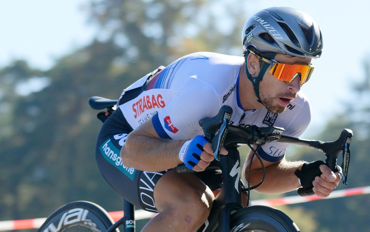 Peter Sagan rides a black road bike in a "supertuck" position.