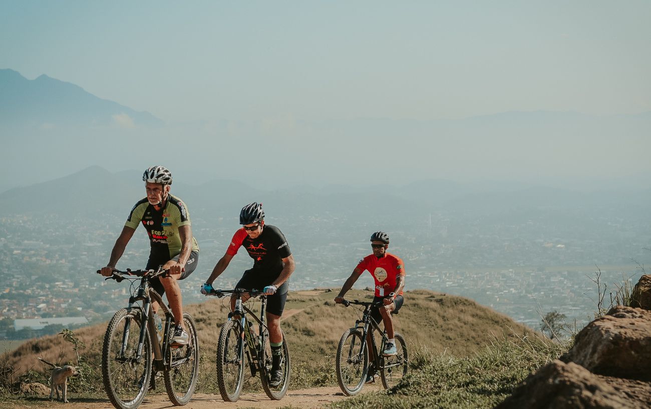 Three men on mountain bikes cycle up a hill while wearing cycling shorts, an effective prevention method for saddle sores.