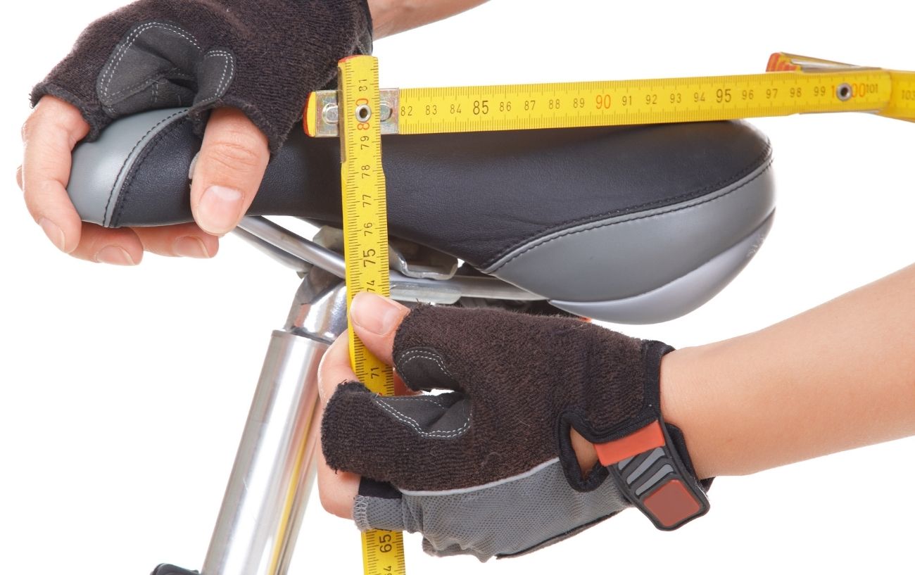 A person measures the height of a bicycle saddle on a bike.