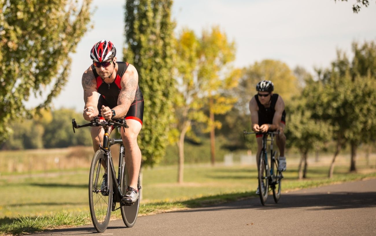 A man wearing red and black cycles on a black triathlon bicycle.