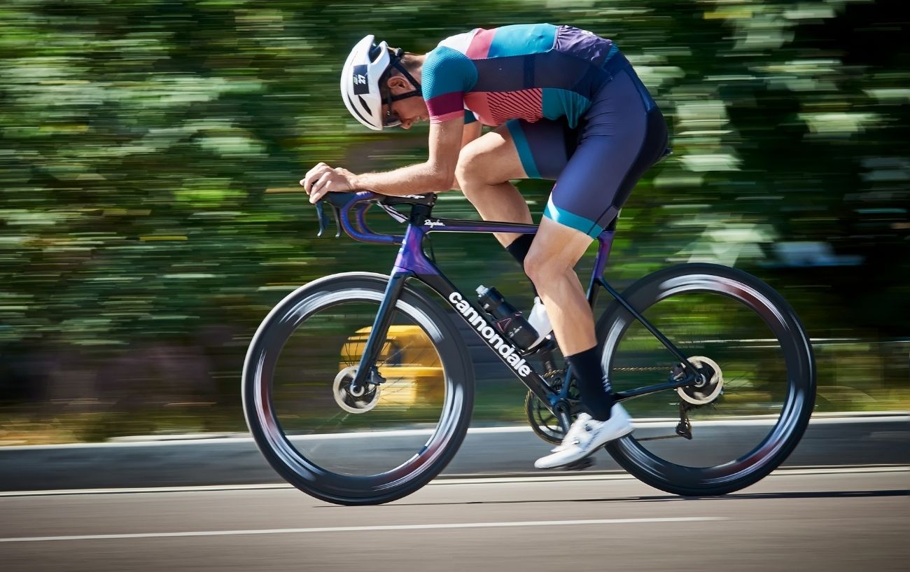 A cyclist rides on a purple bicycle with a blurred background.