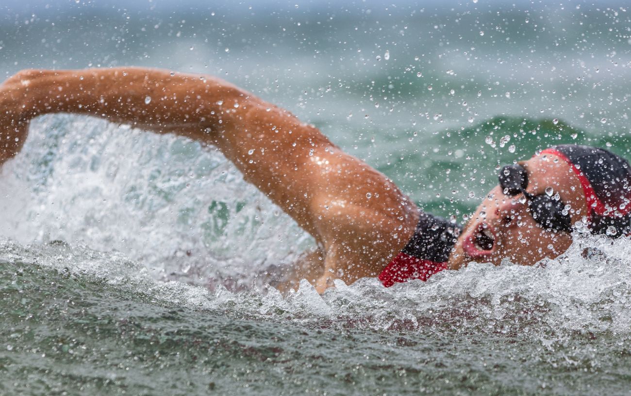 A swimmer wearing red and black does the front crawl through the water.