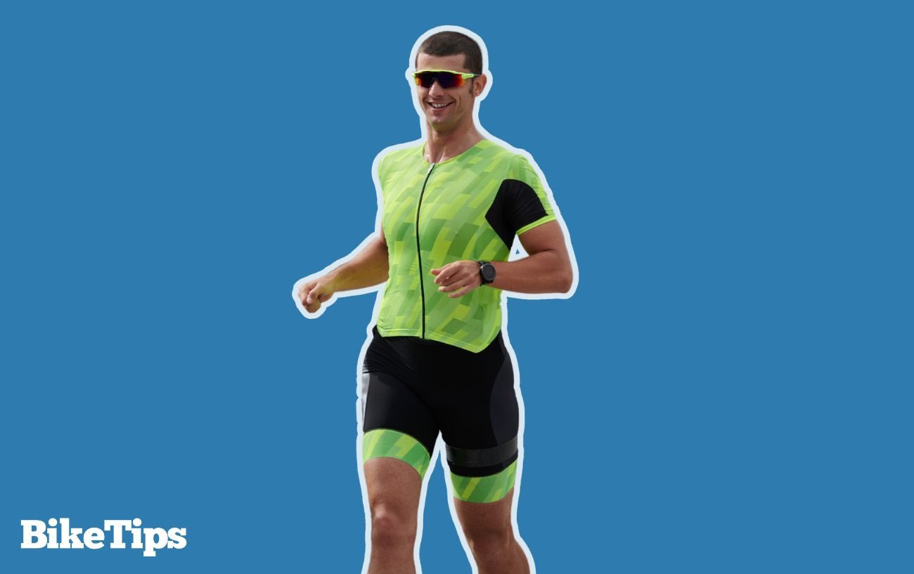 A triathlete in a green tri-suit running with sunglasses on.