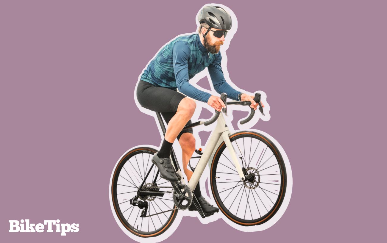 A cyclist pedals uphill on a white road bike while changing gear.