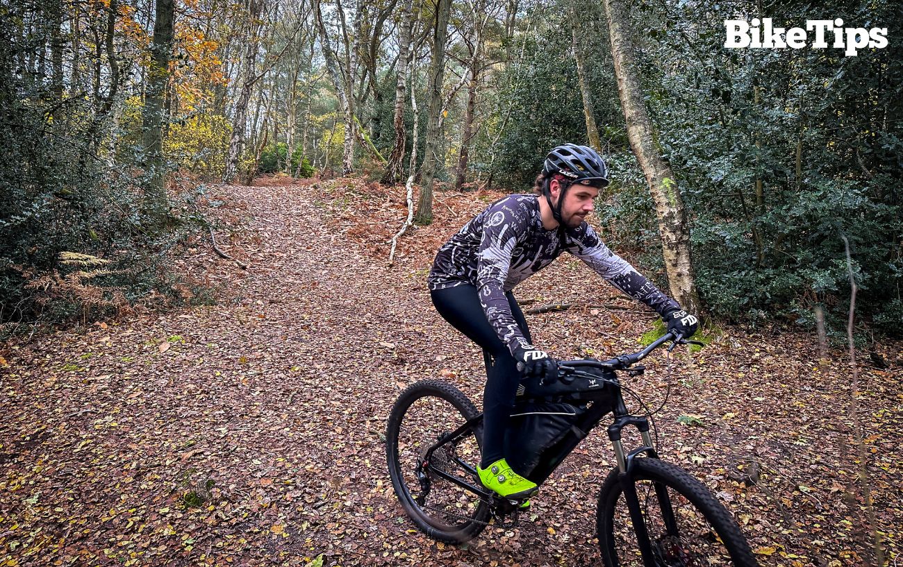 Robbie rides a mountain bike while wearing a black bike helmet.