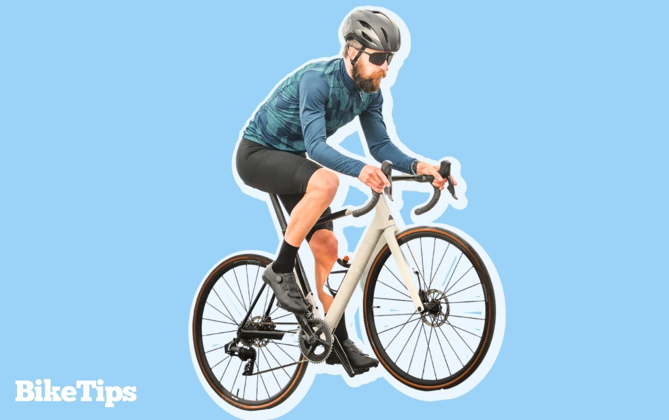 A male cyclist rides uphill, demonstrating some of the effects of cycling on body shape.